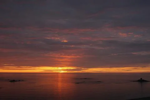 Seascape with dark clouds and setting sun Stock Photos