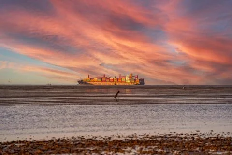 Seascape with dramatic sky, a container ship driving along the horizon Stock Photos