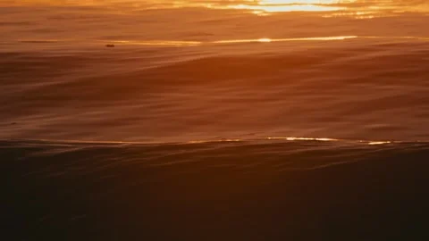 Seascape featuring luminous currents blending with warm orange hues at dusk Stock Footage 322033565