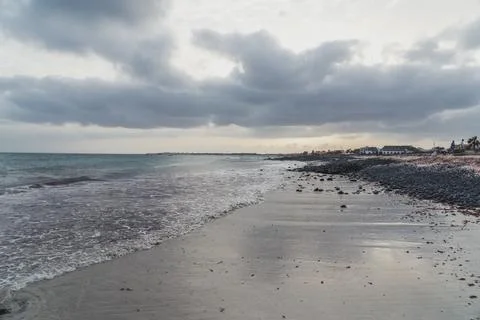 Seascape with ocean and beach in the foreground on a moody cloudy day Stock Photos