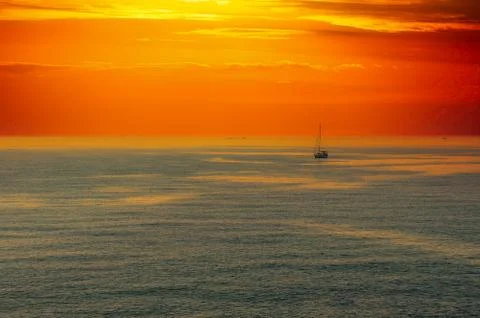 Seascape at sunset with dramatic red sky and sail boat Foto stock