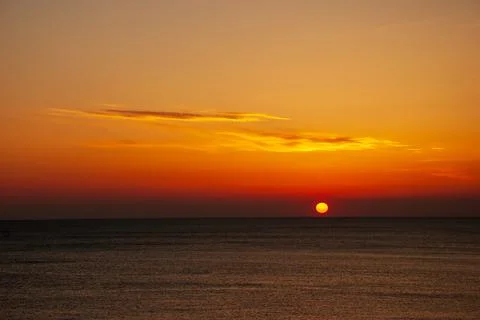 Seascape at sunset. The red disk of the sun is beyond the horizon. Stock Photos