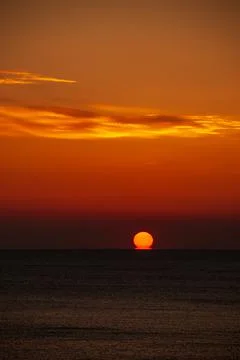 Seascape at sunset. The red disk of the sun is beyond the horizon. Stock Photos