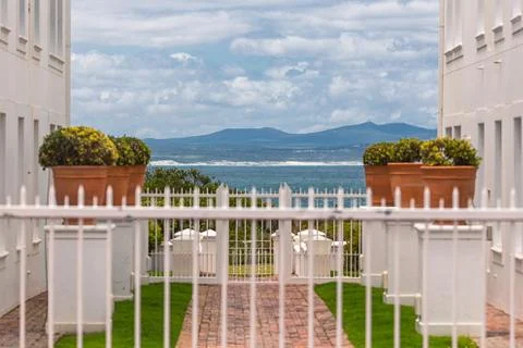 Seascape view between two white buildings and blured white fence in foregroun Stock Photos