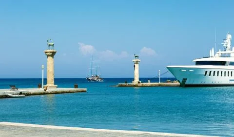 Seascape view on deer statues and ships at the enrance to the Mandraki Harbou Foto stock