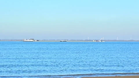 Seascape view with long cargo vessel sailing and wind mills on horizon Stock-Footage 301569236