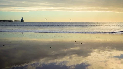 Seascape with waves, the lighthouse and the sky reflected in the wet sand Stock Footage 129127626
