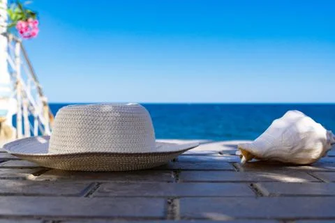 Seashell and hat on the background of the blue sea Stock Photos