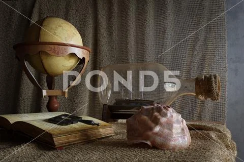 Seashell in interior scene with globe and ship in the bottle concept photo Stock Photos