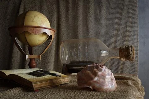 Seashell in interior scene with globe and ship in the bottle concept photo Stock Photos
