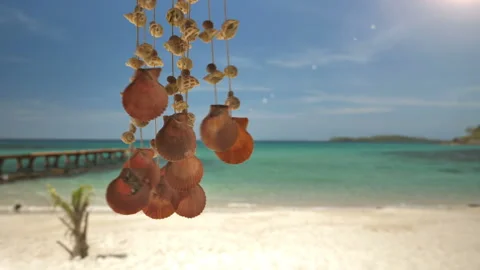 A seashell mobile sways with the wind, on a beautiful  beach of Thailand. Stock Footage 147320498