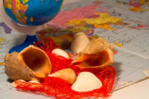 Seashells and small globe on a book with a geographical map. Foto stock