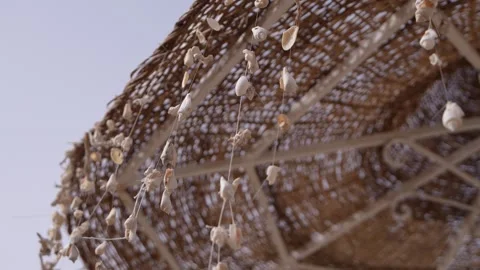 Seashells decorations hanging from a straw umbrella Stock Footage 335998829