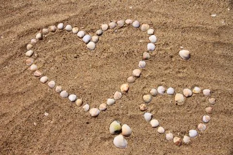 Seashells on the sand in the form of heart Stock Photos
