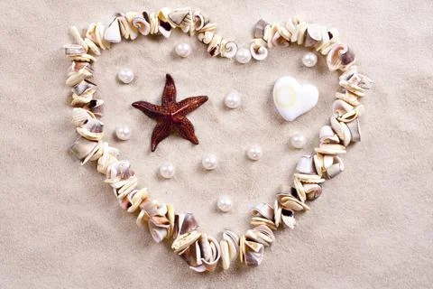 Seashells in sand in the form of heart Stock Photos
