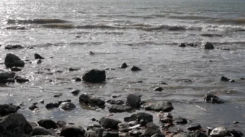 Seashore with small rocks scattered as tiny waves come and go. Contrast Stock Footage 202006788