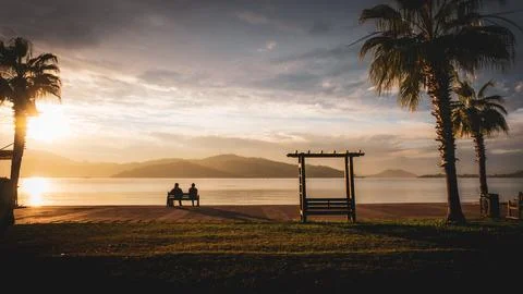 Seashore Sunset with Empty and Occupied Benches Foto stock