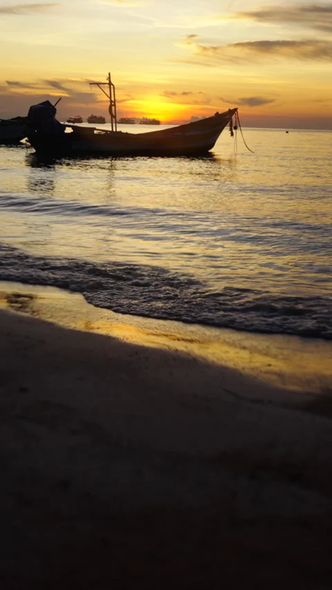 Seashore with waves with boats in the background and a beautiful sunset Video stock 265477723