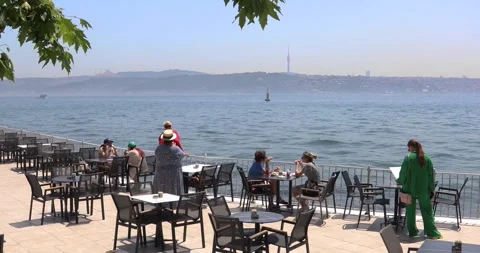 Seaside café on Bosphorus with people dining and hazy Istanbul view Stock Footage 321047672