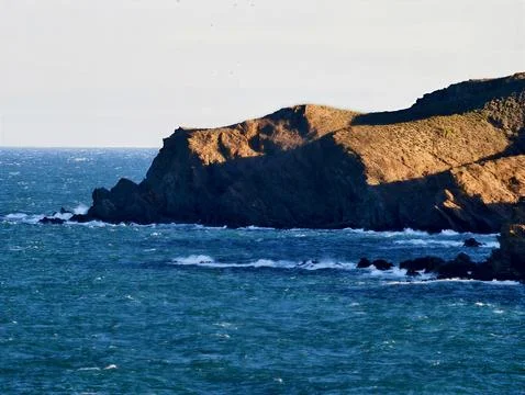 Seaside cliffs with crashing waves. Rugged coastlines overshadowed by fadin.. Stock Photos