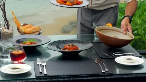 At a seaside restaurant, a waiter serves a table overlooking the ocean Stock Footage 243118596