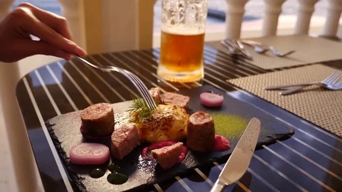 Seaside restaurant. A woman eats meat and drinks beer in a restaurant. Slow Stock Footage
