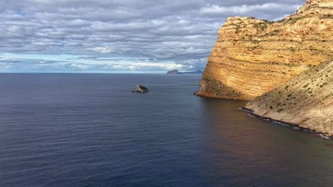 Seaside Rock Formation With Clouds. Quiet Oceanic Column Next To Vibrant Orange Stock Footage 342401237