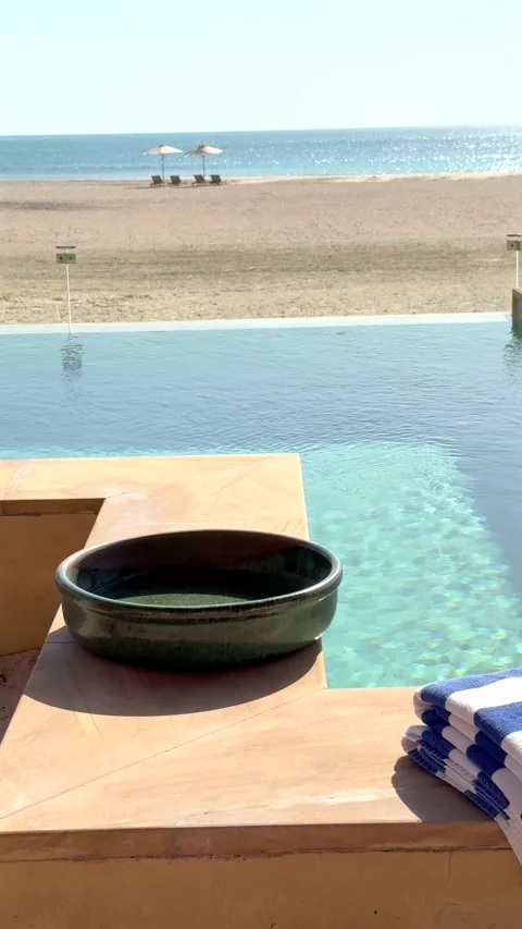 Seaside swimming pool with distant umbrellas and beach beds. Shimmering water Stock-Footage 283248734