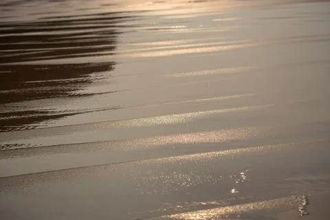 Seaside view with light effects and reflections in the water, wet sand Stock Photos