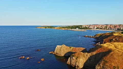 Seaside view from rocky cliffs with clear water and distant town during a sunny Stock Footage 341109143