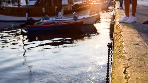 Seaside walkway close up during sunset. Boats in the sea and people walking. Stock Footage 112643148