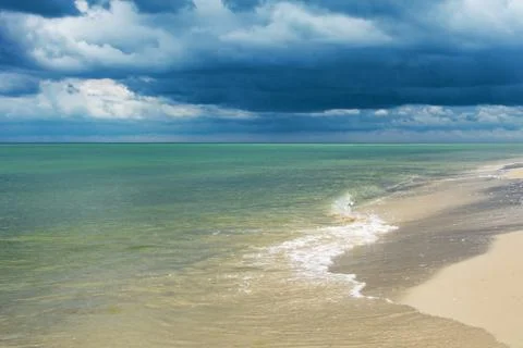 Seaside with waves and dark clouds over water. Stock Photos
