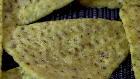 Seasoned triangular corn nacho chip rotating on dark textured background, macro Stock Footage 345610894