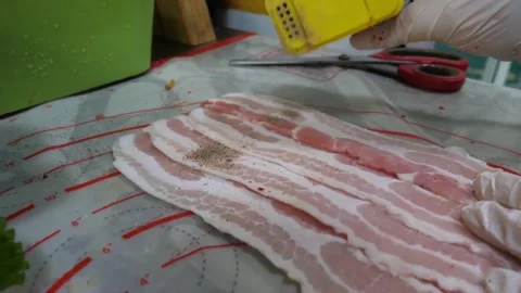 Seasoning Raw Bacon Strips on Prep Mat with Black Pepper 스톡 동영상 343587948