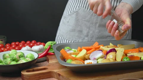 Seasoning with salt and pepper lots of sliced vegetables in an oven pan in 4k. Stock Footage 145115553