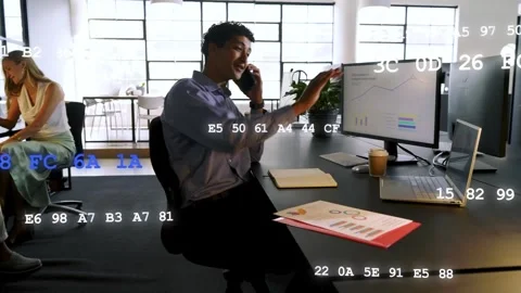 Seated analyst answering call and noting in office, codes scrolling over charts Stock Footage 333689461