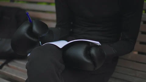 Seated athlete carefully analyzing training plan in peaceful park setting, Calm Stock Footage 330960718