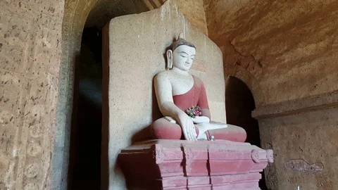 Seated Buddha with painted red robe statue holds flowers in Bagan ancient temple Stockbeeldmateriaal 78887380