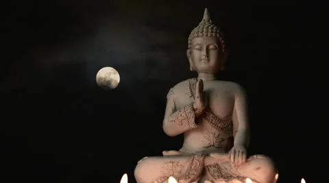 Seated Buddha statue lit by burning candles, composited moon timelapse bg Stock Footage 65524189
