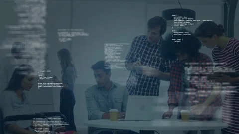 Seated engineer starting laptop, team leaning in at table reviewing app with Stock Footage 334768626