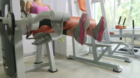 Seated leg extension machine exercise in health fitness club Stock Footage 54992344