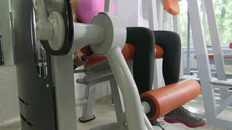Seated leg extension machine exercise in health fitness club Stock Footage 54992361