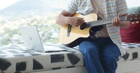 Seated man is placing left hand on neck, causing strumming acoustic guitar for Stock Footage 336368437