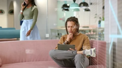 Seated man tapping tablet in tech causing blue overlay checking data woman Stock Footage 330272198