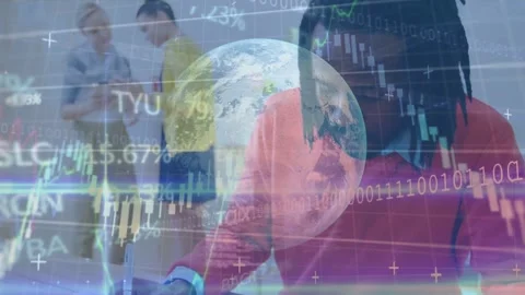 Seated man writing and glancing at phone, causing finance globe charts growing Stock Footage 334703443