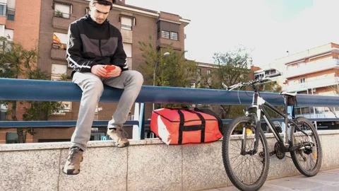 Seated messenger, looking for order address on mobile Stock Footage 145849188