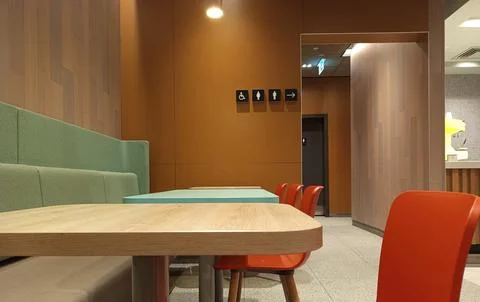 The seating area of a modern cafe features wooden tables and colorful chairs  Stock Photos