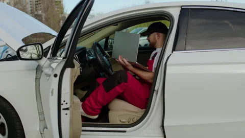 Seating himself inside broken-down car, mechanic initiated diagnostic process Stock Footage 271630029