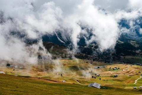 Seceda mountain landscape with dramatic clouds and scattered alpine huts in.. Stock Photos