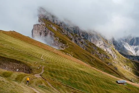 Seceda mountain range in the Dolomites with a lone hiker and a small hut Stock Photos